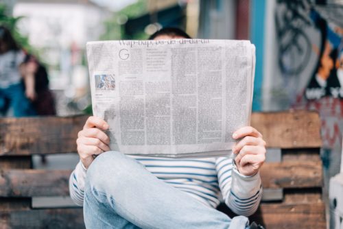 Man reading a newspaper on a park bench