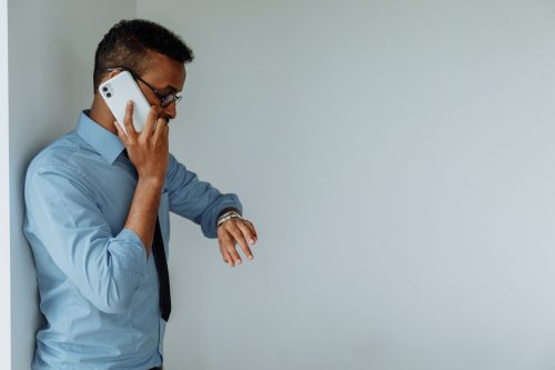 A picture of a man on the phone looking at his watch